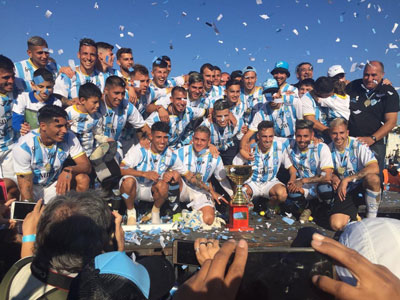 Festejo en la barranca: los jugadores con la copa de campeón de la Primera C.