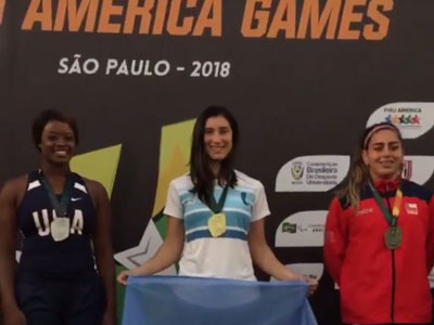 Daniela Gómez luciendo la bandera argentina, en lo más alto del podio.